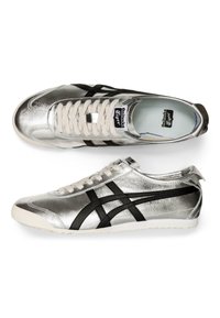 Srebrne buty sportowe z czarnymi paskami, metaliczne wykończenie, sznurowany design i gumowa podeszwa. Posiadają wyściełany kołnierz i język.