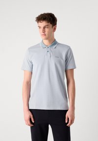 Lyseblå polo skjorte med kontrastfarge på kragen og kantene, med en tre-knaps placket og en liten logo på brystet. Korte ermer.