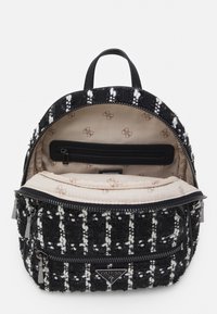 Czarnobiały plecak o fakturowanej powierzchni wykonany z tkanego materiału, wyposażony w zamykaną na zamek główną przegrodę, wewnętrzną kieszeń oraz markowe detale.