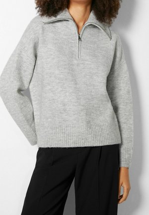 Sweter w kolorze jasnoszarym, z kołnierzem zapinanym na suwak do połowy, prążkowanym dołem i szerokimi rękawami, wykonany z miękkiej, teksturowanej tkaniny.