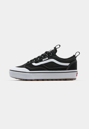 Black canvas sneaker with white accents, rubber sole, stitched detail, and lace-up design. Features a pull tab on the heel for easy wear.