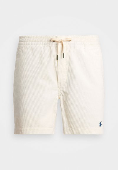 Bež prugasti kopalni šorc z elastičnim pasom in vrvico, ki ima majhen moder logotip na spodnji strani.