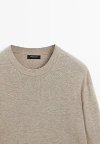 Beige sweater with a round neckline and ribbed cuffs. Made of textured knit fabric. Label reads "Massimo Dutti."