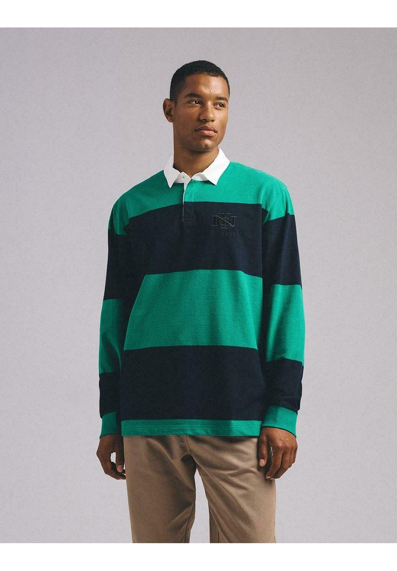 Koszulka rugby z długim rękawem w zielono-granatowe paski, z białym kołnierzykiem i haftowanym logo na piersi. Miękka tekstura materiału.