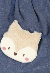 Měkký béžový pouch ve tvaru lišky, s nadýchanou texturou, růžovými tvářemi a vyšitýma obličejovými rysy. Připevněný popruh v námořnické modři.