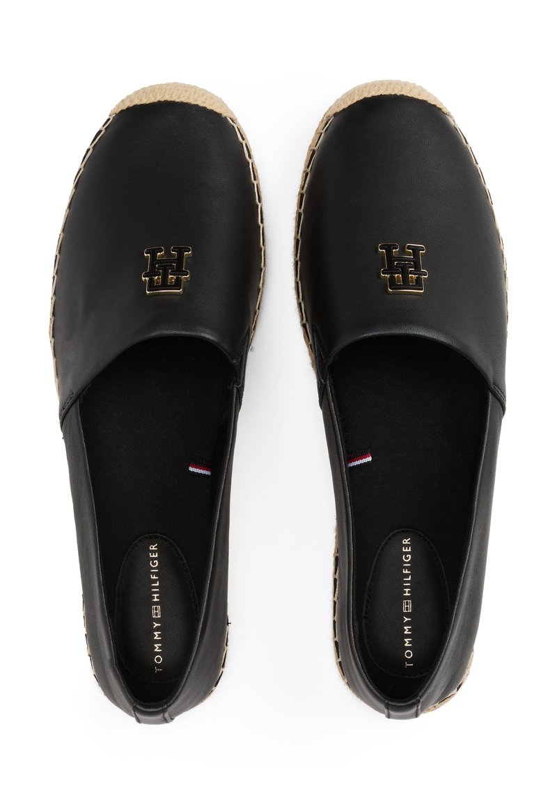 Espadrilles en cuir noir avec une semelle en jute tissée. Présentent un logo doré sur le dessus et un intérieur en tissu noir texturé. Design classique à enfiler.