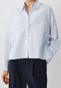 Ljusblå knapp-up skjorta med rutmönster, långa ärmar, krage och en avslappnad passform. Tillverkad av mjukt, lätt tyg.