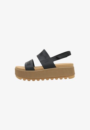 Sandalo platform nero con suola spessa scanalata color cuoio, due fascia larghe sul piede e cinturino posteriore regolabile con chiusura in velcro.