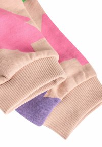 Villatakki beige-värissä, jossa on vaaleanpunaisia ja purppuranvärisiä geometrisia kuvioita. Rypytetyt hihansuut antavat rakenteellista ilmettä. Pehmeä kangas, jolla on sileä pinta.