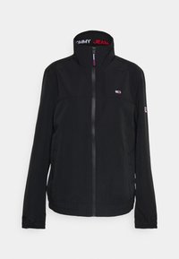 Černá bunda vyrobená z lehkého materiálu, s vysokým límcem, zipovým zapínáním a elastickými manžetami. Na límci a rukávu vyšívané logo Tommy Jeans.