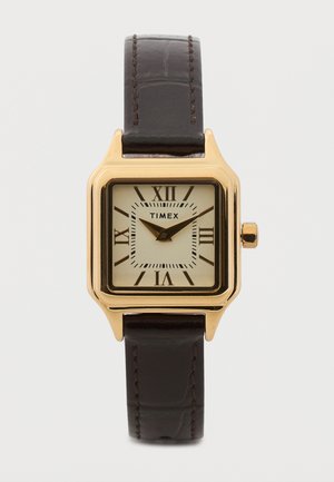 Neliömäinen kultainen Timex-kello, jossa on kermanvärinen kellotaulu, mustat roomalaiset numerot, mustat tunti- ja minuuttiviisarit sekä tummanruskea nahkaranneke.