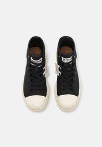 Czarne wysokie trampki z kremową gumową osłoną na nosku, teksturowanym materiałowym cholewką, wiązane na sznurówki oraz korkową wkładką. Dołączone dwa metki.