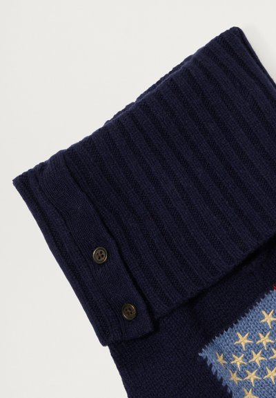 Cuello de suéter de punto navy con textura acanalada, que presenta dos botones oscuros. Incluye un parche azul con un diseño de estrellas amarillas en el cuerpo.
