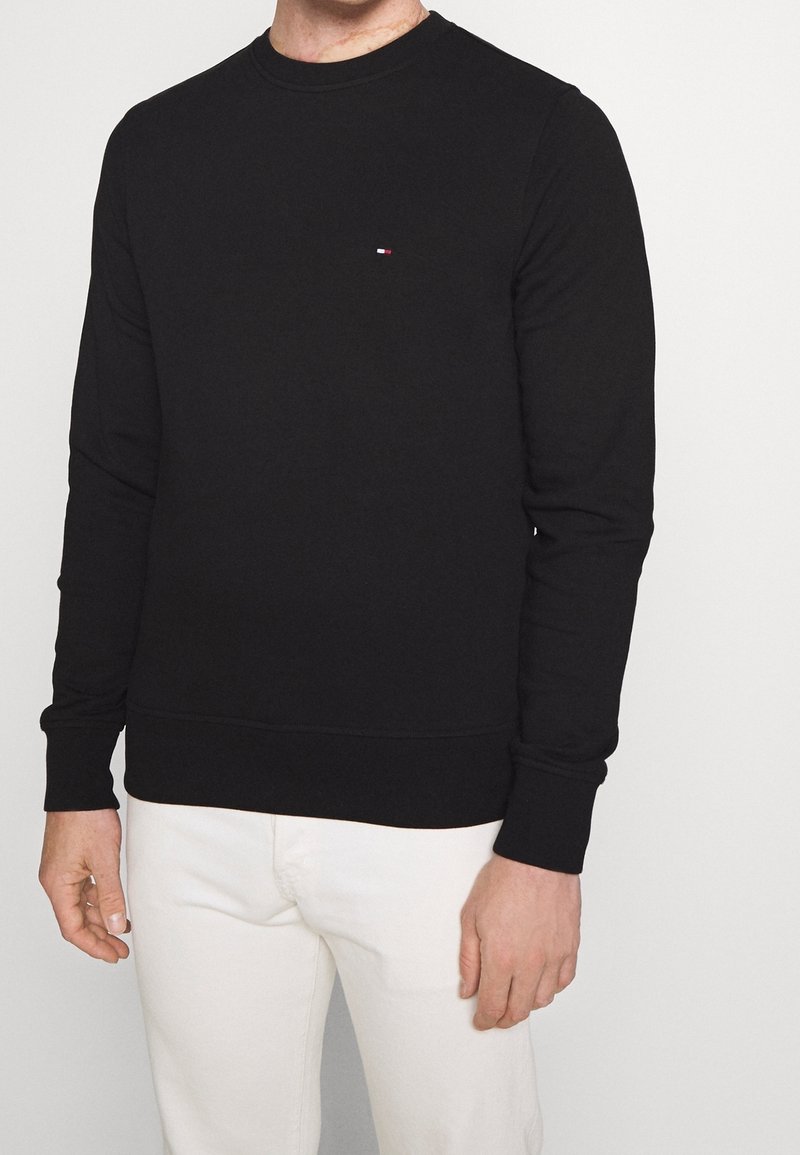 Felpa nera, in misto cotone, con collo tondo e maniche lunghe, caratterizzata da un discreto ricamo del logo in rosso, bianco e blu sul petto.