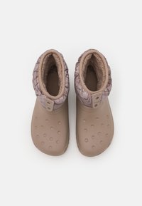 Botas impermeáveis castanhas com um topo texturizado e furos redondos. O interior é forrado com lã suave, apresentando dois detalhes em botão.