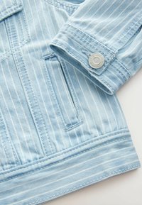 Lichtblauwe denim jack met verticale strepen, voorzien van een metalen drukknoopsluiting en een gladde textuur. De mouwen en de zoom hebben stiksels als accent.