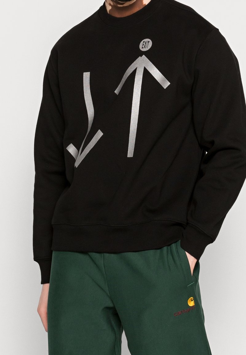 Sort sweatshirt med sølvfarvet grafisk motiv med pile og et "EXIT"-mærke. Blødt materiale med afslappet pasform og ribstrikkede manchetter.