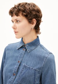 Lichtblauwe denim overhemd met een kraag, knoopsluiting en een borstzak. Beschikt over zichtbare stiksels en een gestructureerde stof.