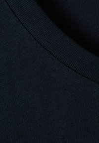 Primer plano de una tela de punto azul marino oscuro con un escote acanalado, mostrando textura y detalles de costura.