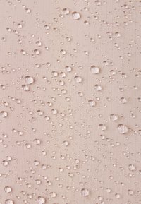 Beige szövet, amelynek texturált felülete van, és amelyen számos különböző méretű, áttetsző vízcsepp található egyenletesen elosztva.