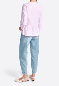 Růžová pruhovaná blůza s peplum pasem, kombinovaná s světle modrými volnými džíny a béžovými balerínami s černými akcenty.