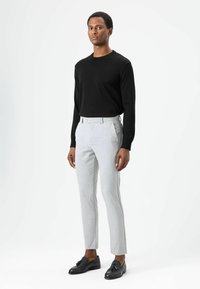 Zwarte lange mouwen shirt gecombineerd met lichtgrijze, op maat gemaakte broek en zwarte nette schoenen, met een slanke pasvorm en strakke lijnen.