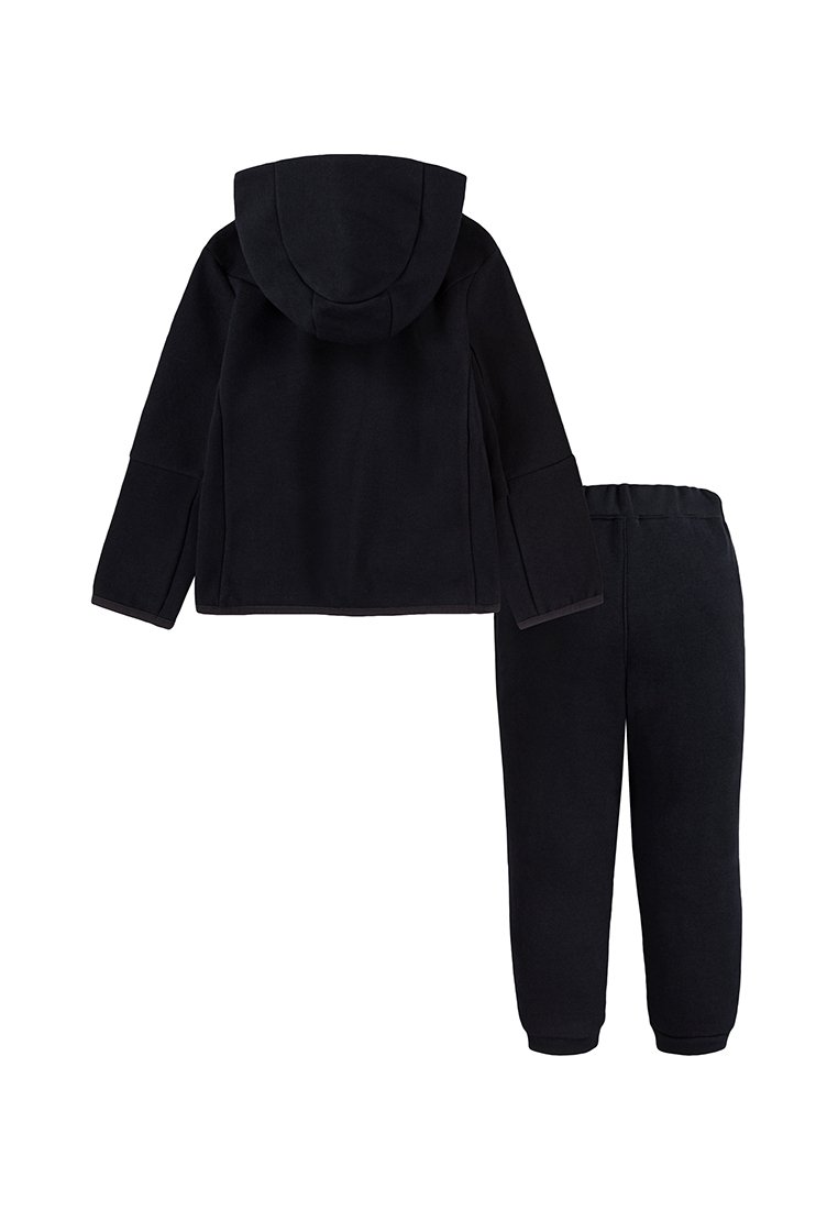 Sweat à capuche en polaire noire avec un capuchon et un pantalon ajusté assorti. Le tissu est doux et texturé, conçu pour le confort et la chaleur.