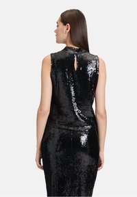 Schwarzes, paillettenbesetztes, ärmelloses Top mit hohem Kragen, Rückenschlitzdetail und taillierter Silhouette, ergänzt durch einen passenden Rock.