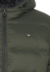 Olive green puffer jacket with a zip closure, adjustable hood, and black hardware. Features horizontal stitching and a small logo detail.
