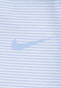 Tela a rayas azul claro con una textura suave presenta un prominente logo de swoosh de Nike en azul pálido.