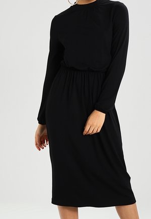 Zwarte jurk met lange mouwen, een ronde hals, plooidetails bij de taille en een losse pasvorm, gemaakt van zachte, gestructureerde stof.