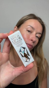 Olio Labbra Magico di Charlotte in una scatola bianca, con un design cristallo olografico e accenti neri e testo. Contiene 8 mL / 0,27 fl oz.