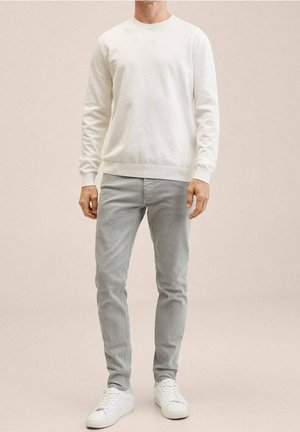White crewneck sweatshirt, light gray slim-fit pants, and white sneakers. Smooth fabric texture; simple design without patterns or accents.