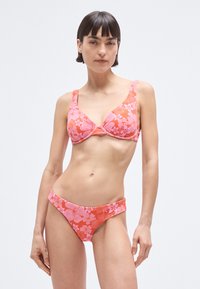 Floral bikini set featuring a bralette with adjustable straps and a low-rise bottom. Colors include bright pink and coral with a textured pattern.