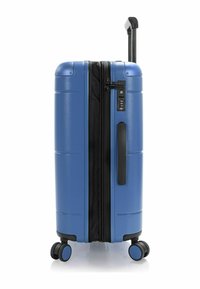 Valise rigide bleue avec une poignée télescopique, serrure et fermeture éclair noire. Quatre roulettes avec des accents bleus. Texture lisse et design épuré.