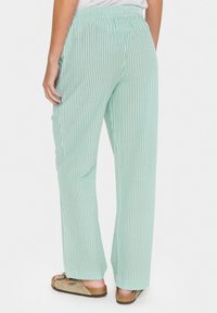 Pantalons rayés vert clair à coupe décontractée, avec une taille élastique et des poches latérales, en tissu doux. Accentué de rayures blanches verticales.