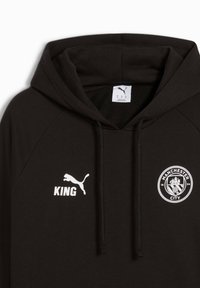 Sort hættejakke med kængurulomme, der har et hvidt Puma-logo, teksten "KING" og Manchester Citys klubmærke på forsiden. Fremstillet af bomuldsstof.