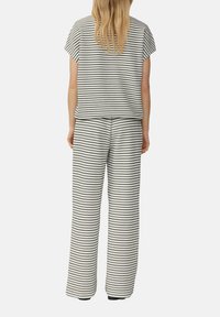 Czarny i biały zestaw z pasami: dopasowana góra i szerokie spodnie z krótkim rękawem oraz luźnym krojem. Materiał podobny do bawełny z fakturowanym wzorem.