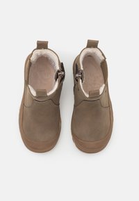 Brązowe botki sięgające kostki, wykonane z gładkiej skóry, z futrzanym wnętrzem, bocznymi zamkami błyskawicznymi oraz okrągłym noskiem.