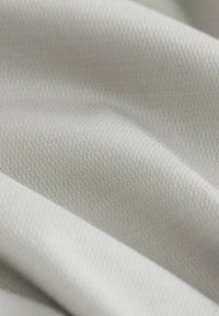 Helles graues Gewebe mit einer strukturierten Oberfläche und einem subtilen diagonalen Muster. Weiche, glatte Textur mit einem leichten Glanz.