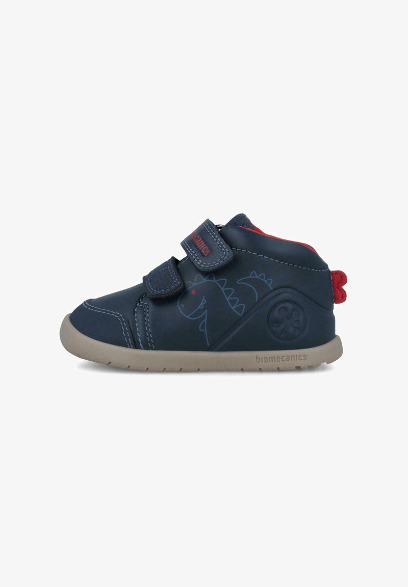 Zapatos de cuero azul para niños con detalles rojos, correas de velcro, estampado de dinosaurios y una suela de goma beige con un detalle de logo en el costado.