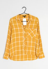 Žlutá kostkovaná košile s dlouhým rukávem a límečkem, s knoflíkovým zapínáním, jednou náprsní kapsou a bílým kostkovaným vzorem. Měkká tkanina s volným střihem.