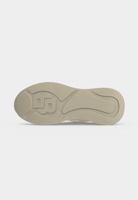 Semelle de chaussure beige avec des rainures courbes texturées et un logo en relief "BG" près du talon pour l'adhérence et l'identification de la marque.
