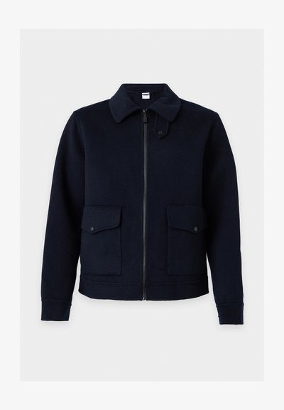 Veste bleu marine foncé avec fermeture éclair sur le devant, deux poches à rabat avec pressions et un col avec une sangle réglable.