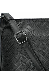 Bolso de hombro de cuero negro con un patrón embossado geométrico, una correa ajustable con una hebilla de metal y una textura lisa.