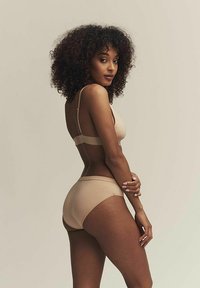 Ensemble de lingerie couleur chair comprenant un soutien-gorge rembourré avec des bretelles réglables et un bas de bikini assorti. Tissu doux et design sans couture.