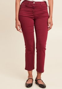 Bordeaux skinny jeans van denim. Middenhoogte taille met vijf-pocket ontwerp en gestikte details. Draag met zwarte flats.