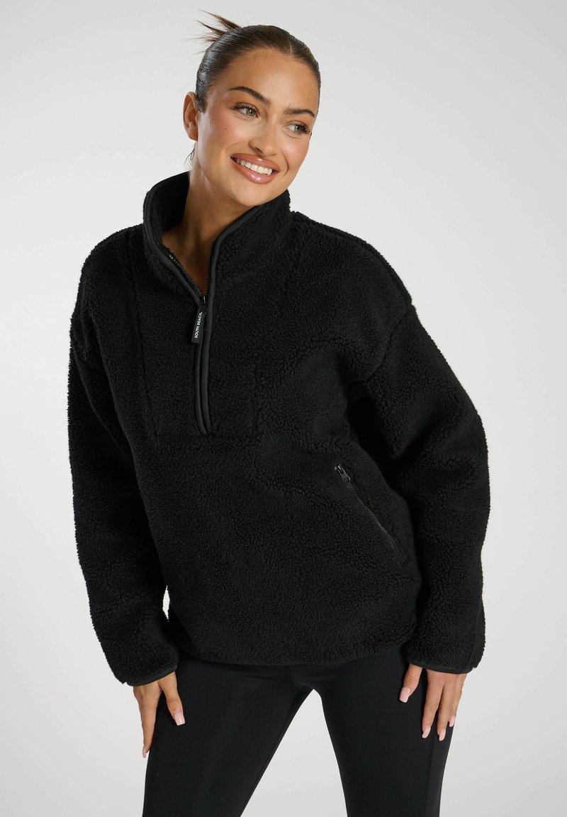 Pullover in pile nero con colletto alto e chiusura a mezza zip. Caratterizzato da una superficie testurizzata e tasca laterale con zip per funzionalità.