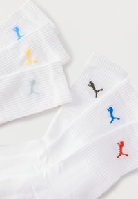 Έξι ζευγάρια λευκές ριγέ κάλτσες μέσης, τοποθετημένες σε δύο σειρές, κάθε ζευγάρι με ένα μικρό λογότυπο Puma σε διαφορετικά χρώματα στη μανσέτα.