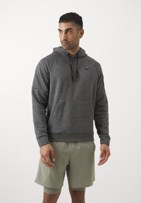 Grå hættetrøje med kængurulomme, sweatstof og justerbar snor i hætten. Har et sort Nike-logo på brystet og ribbede manchetter.
